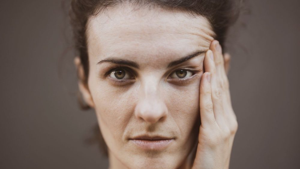 Close-up portrait of a woman with her hand to her face