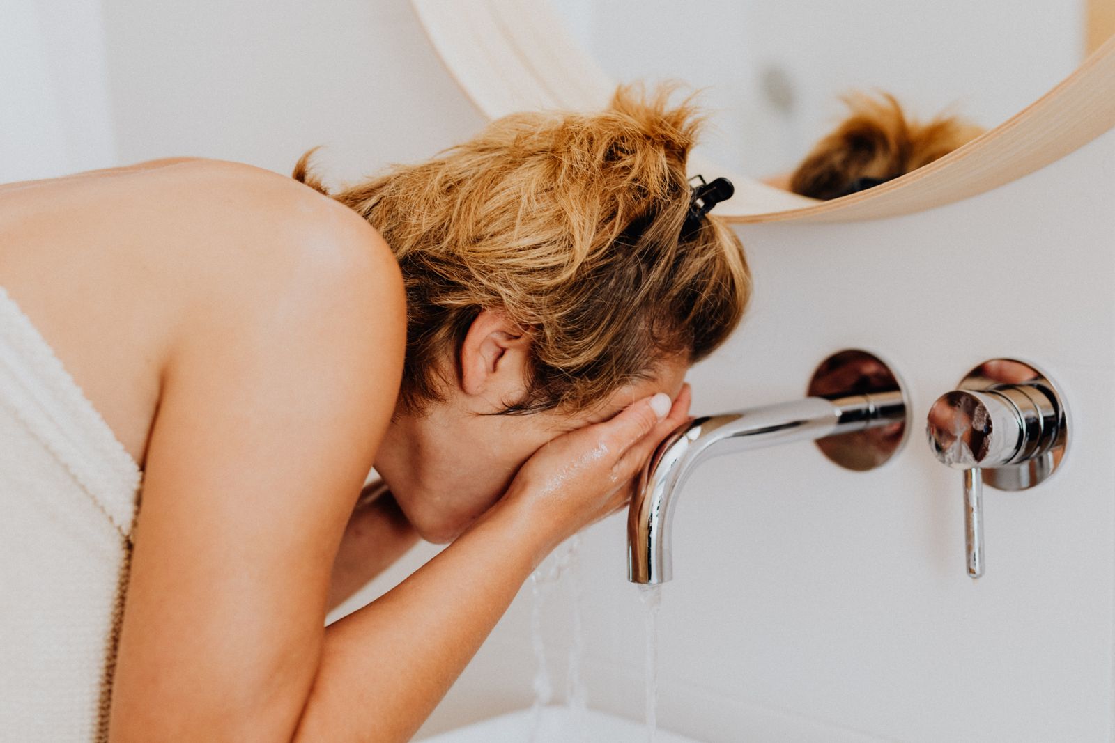 Woman washing her face at a bathroom sink