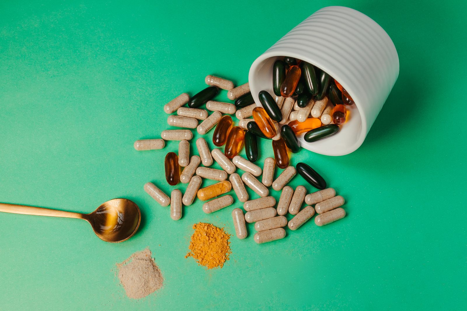 Supplement capsules and powder spilling from a jar