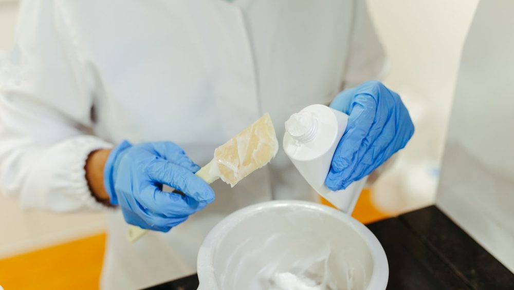 Gloved hands mixing a skincare cream in a laboratory
