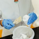 Gloved hands mixing a skincare cream in a laboratory