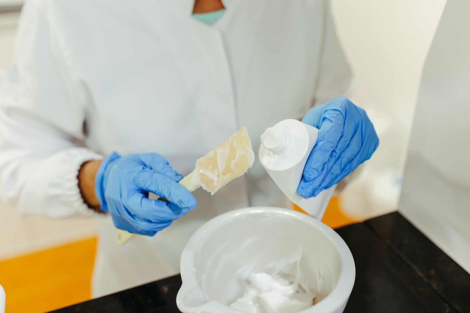 Gloved hands mixing a skincare cream in a laboratory