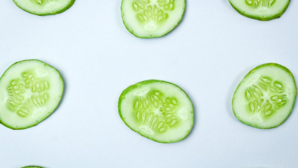 Fresh cucumber slices on a pale background
