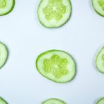 Fresh cucumber slices on a pale background