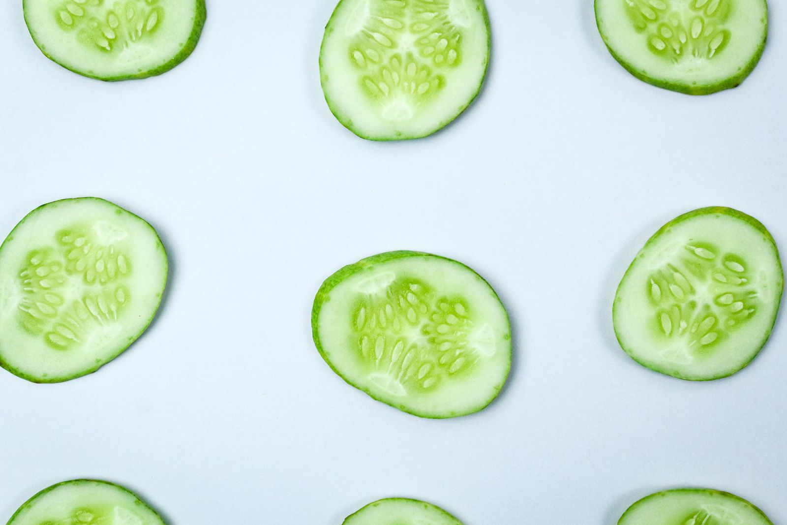 Fresh cucumber slices on a pale background