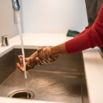 Hands being rinsed under running water at a sink