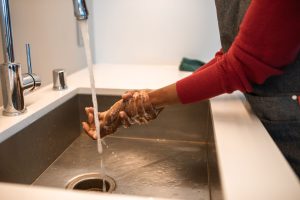 Hands being rinsed under running water at a sink