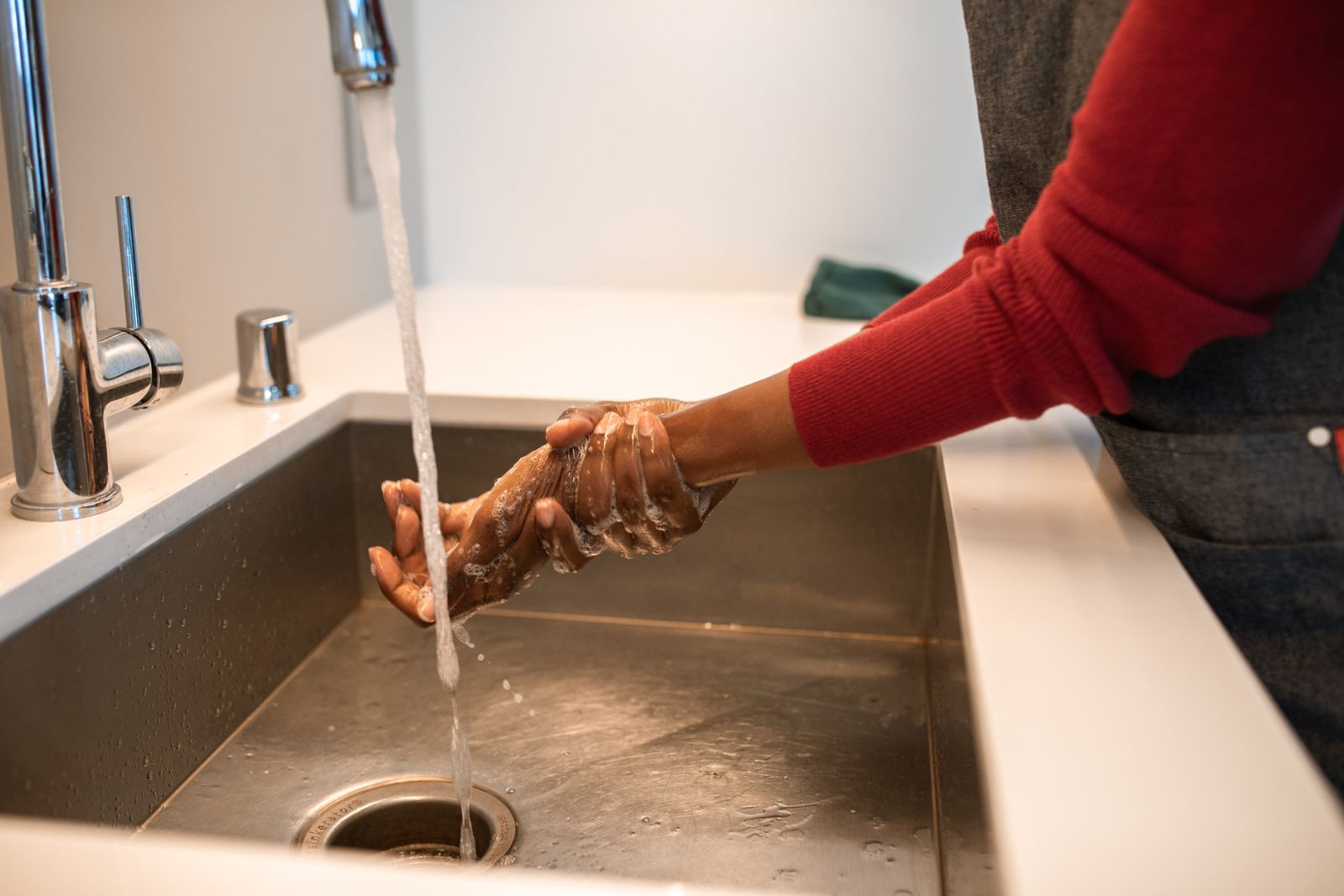 Hands being rinsed under running water at a sink