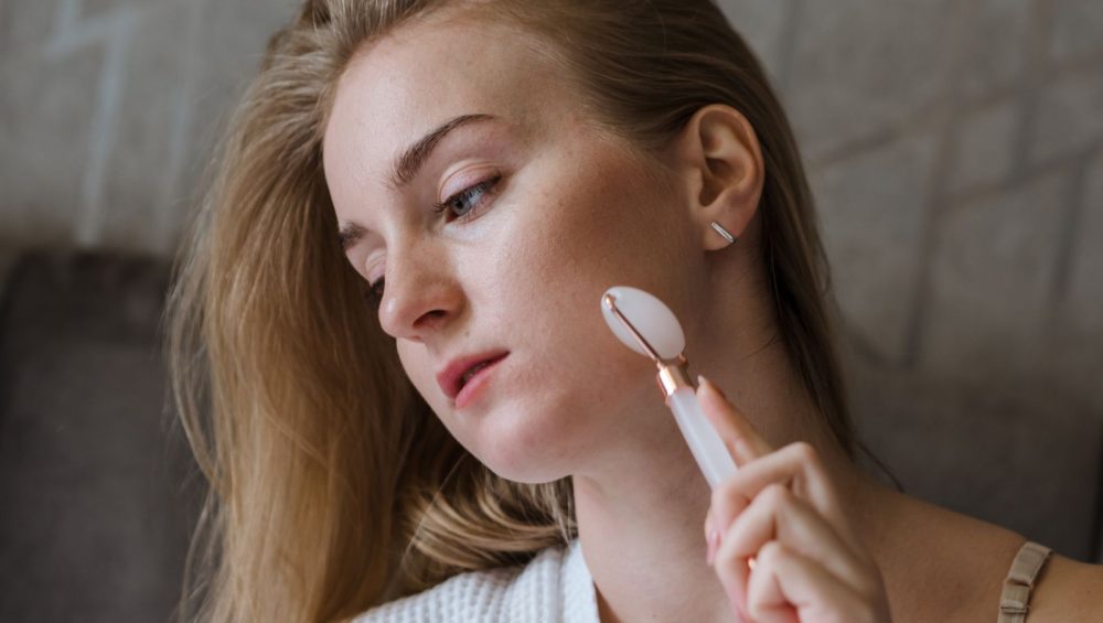 Woman using a facial roller along her cheek