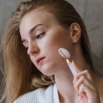 Woman using a facial roller along her cheek
