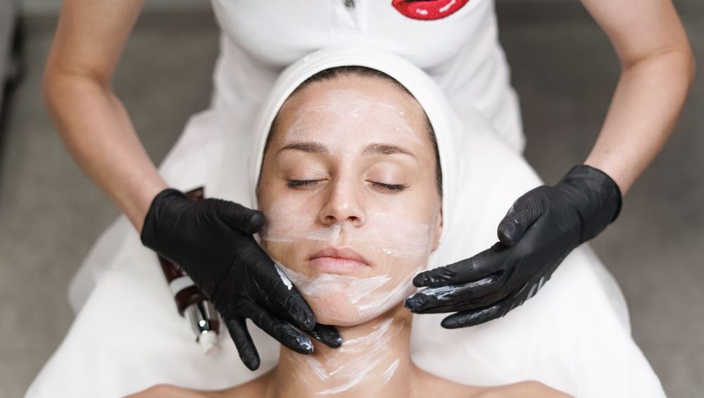 Esthetician performing a facial treatment wearing gloves