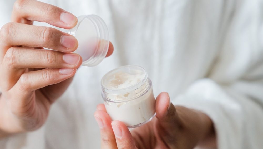 Woman holding an open jar of skincare cream