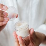Woman holding an open jar of skincare cream