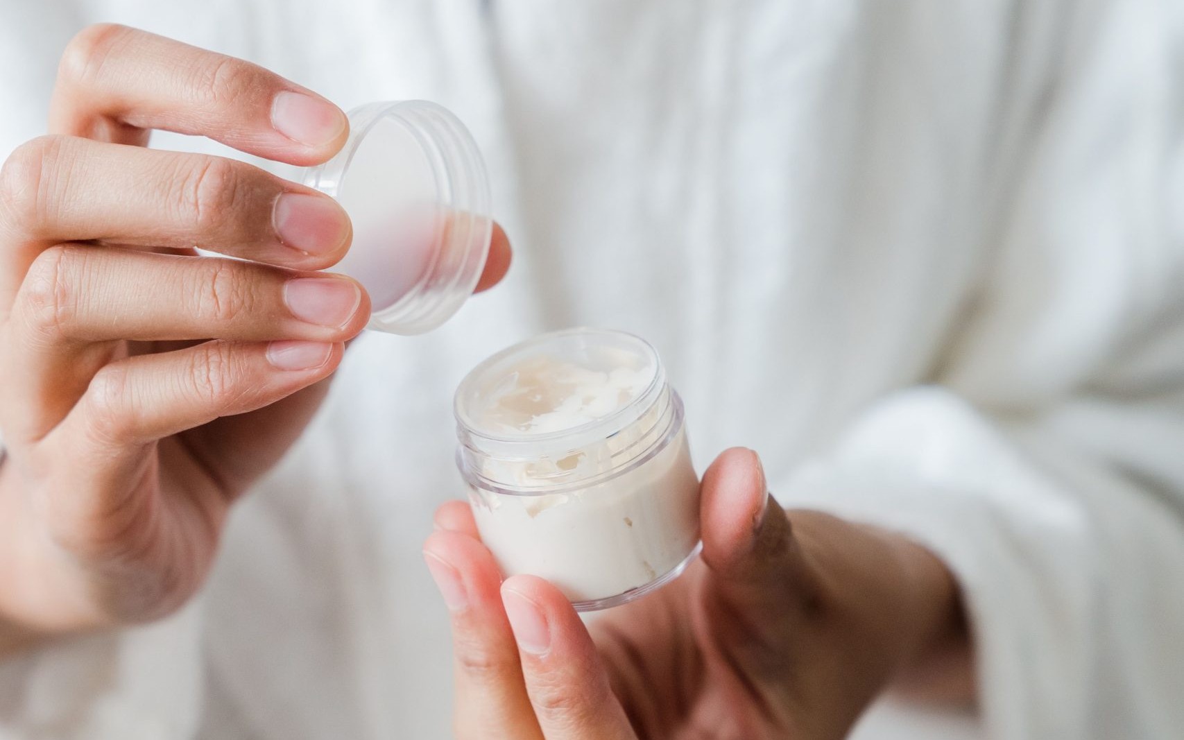 Woman holding an open jar of skincare cream