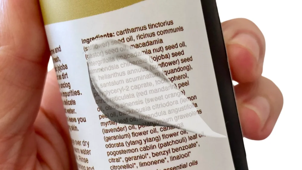 Person reading the ingredient list on a skincare product