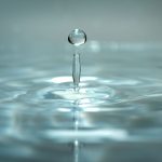 A water droplet falling into water and forming ripples