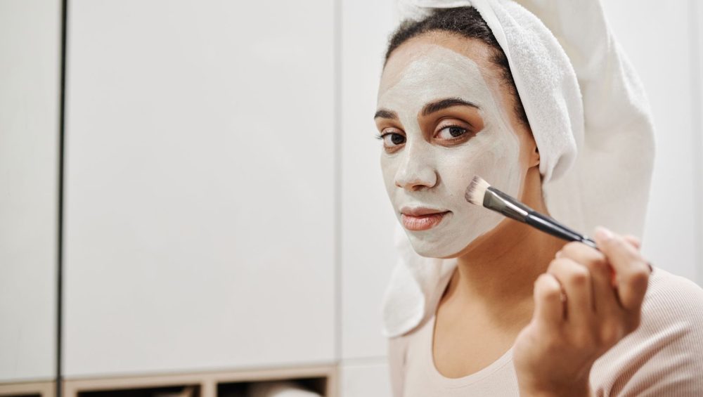 Woman applying a clay face mask with a flat brush