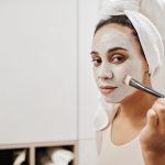 Woman applying a clay face mask with a flat brush