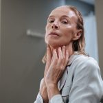 A mature woman applying skincare to her face