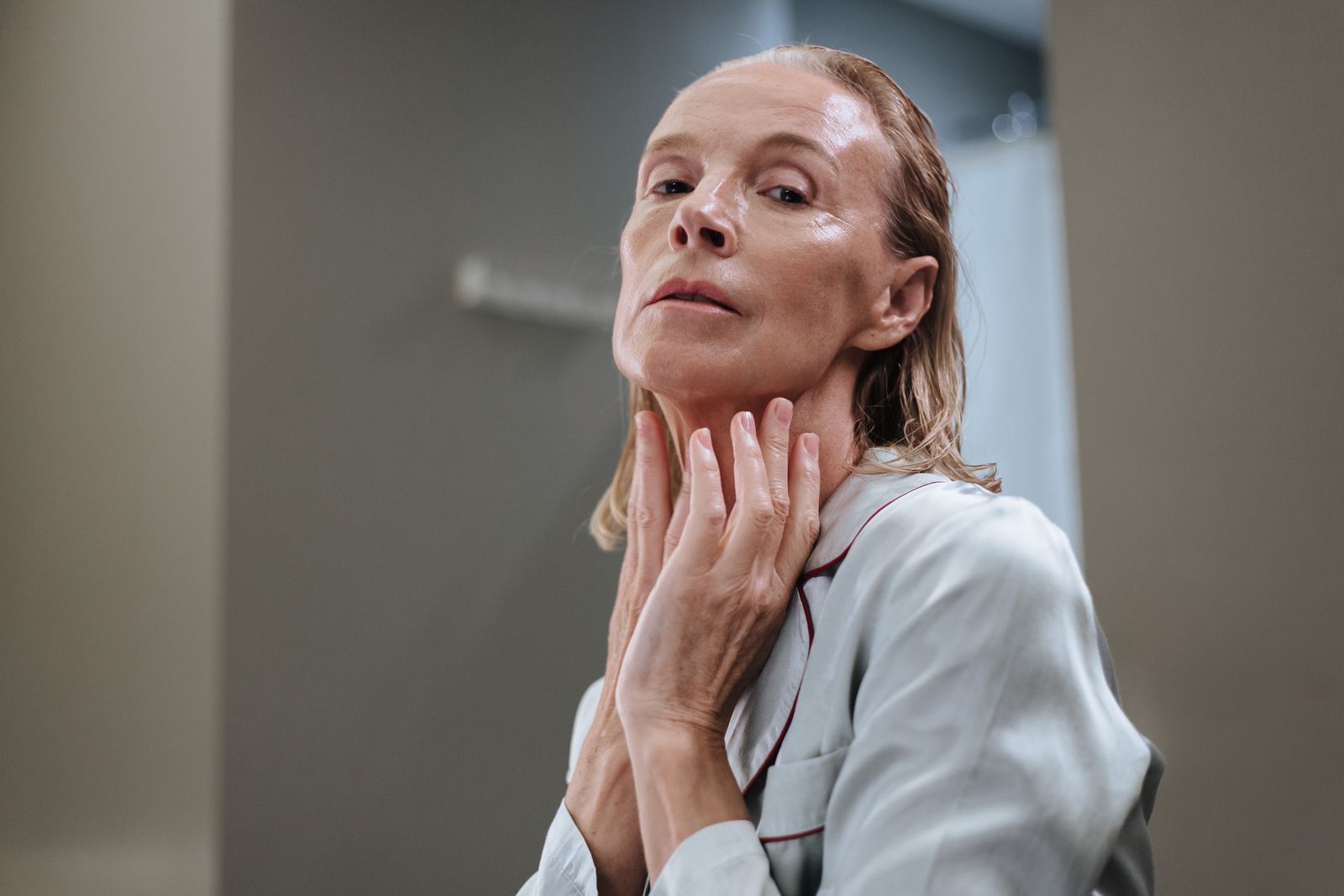 A mature woman applying skincare to her face
