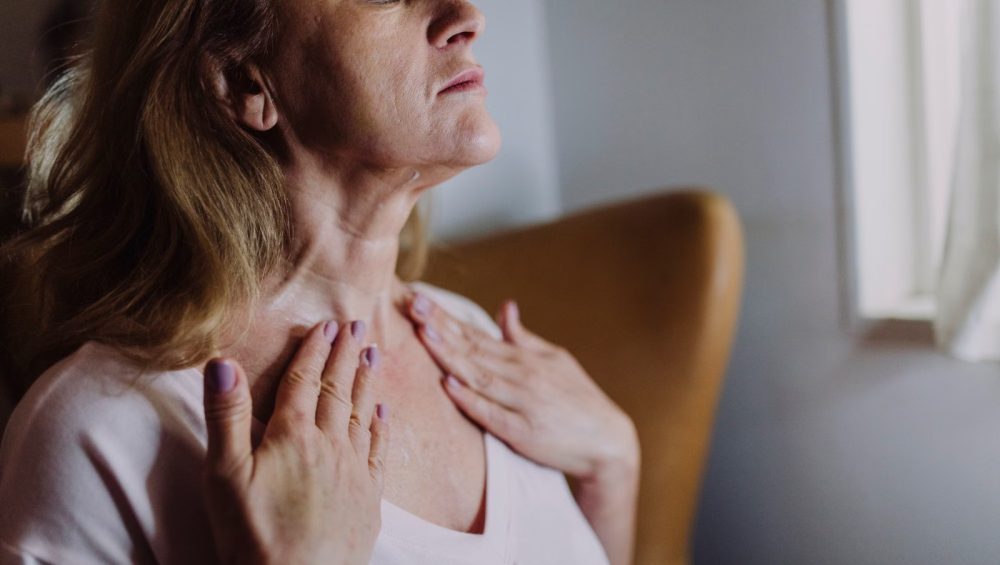 Mature woman applying skincare to her neck and decollete