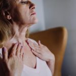 Mature woman applying skincare to her neck and decollete