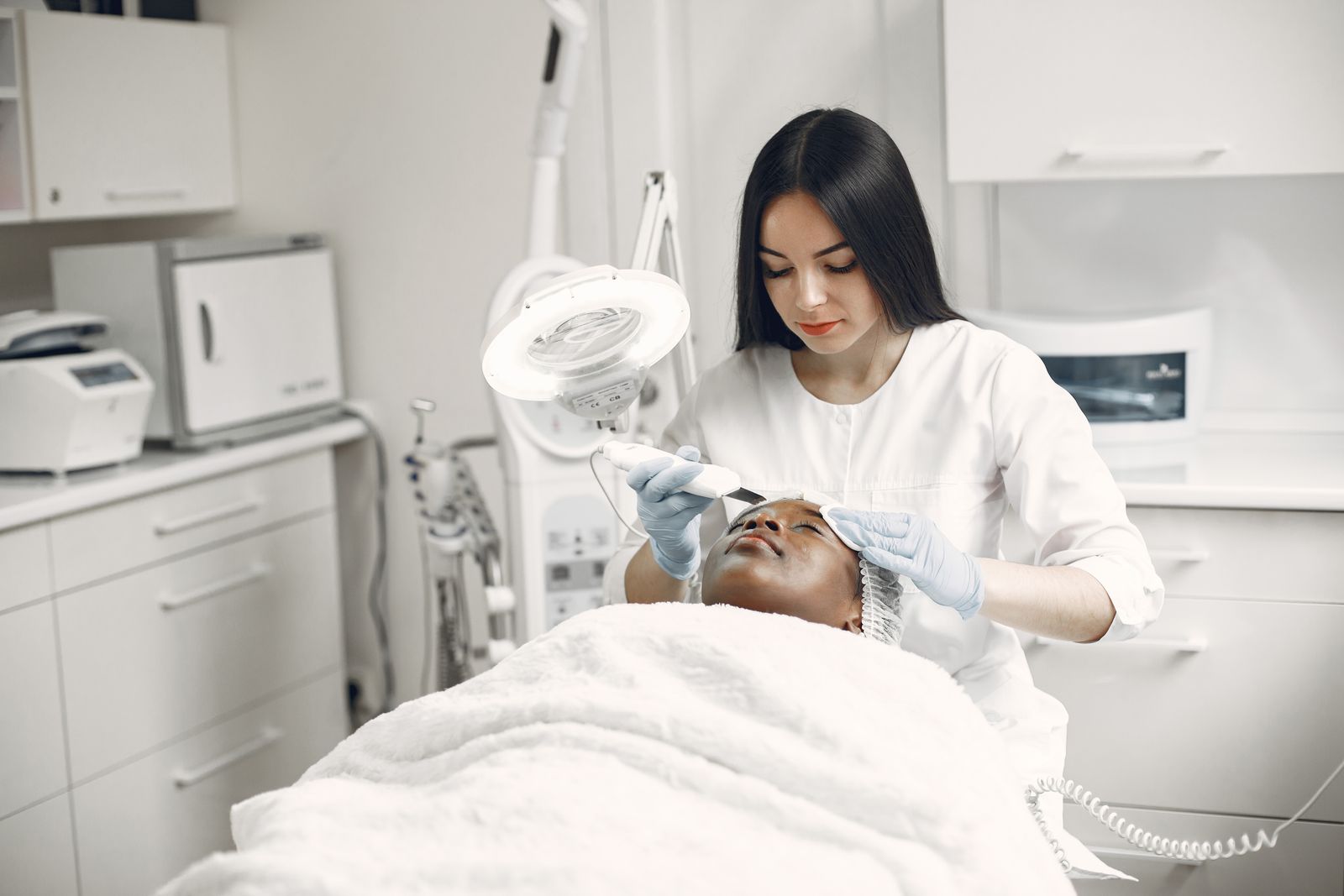 Esthetician performing a facial treatment in a treatment room