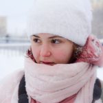 Woman with flushed cheeks wrapped in a scarf outdoors in the snow