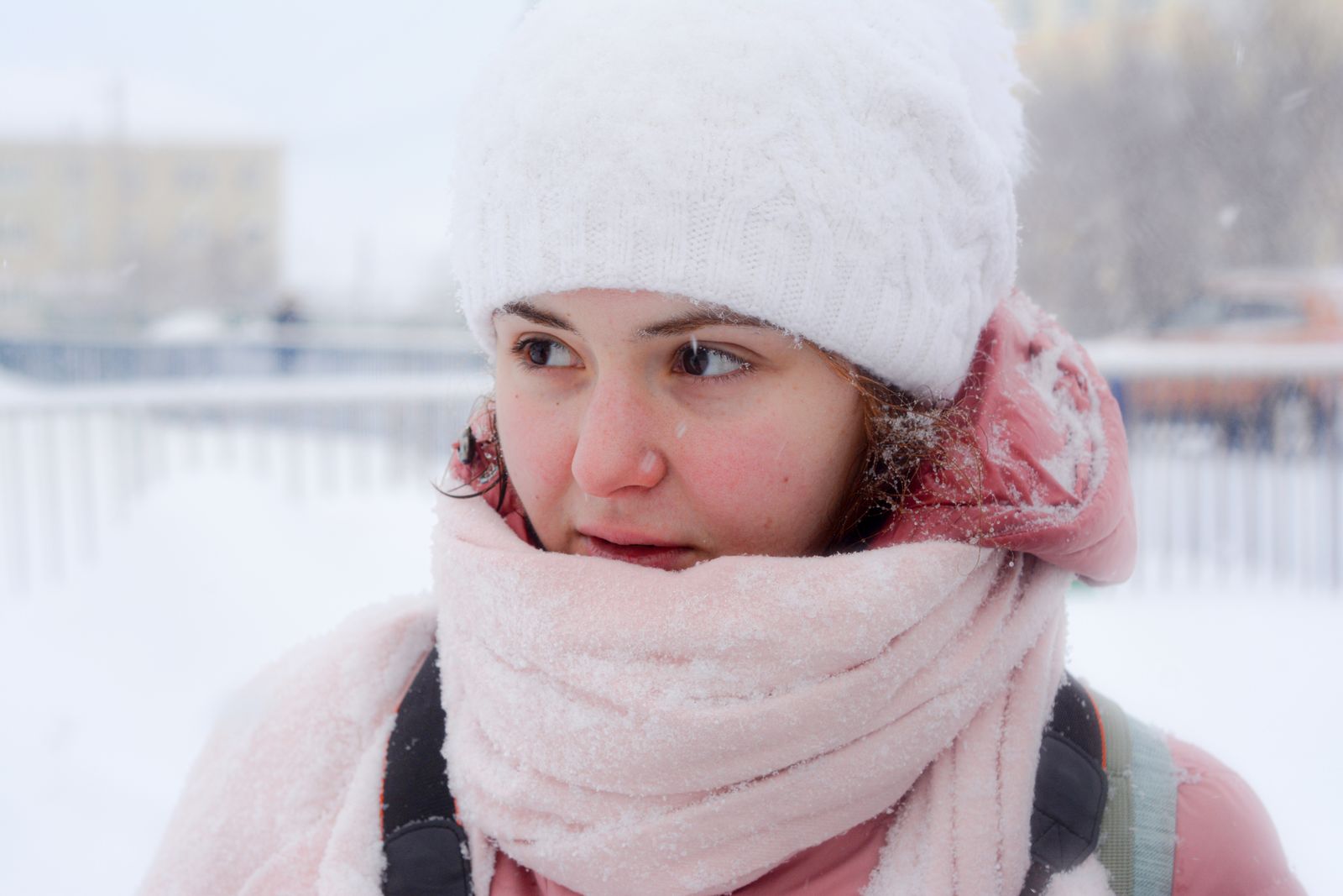 Woman with flushed cheeks wrapped in a scarf outdoors in the snow