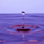 A single drop falling into violet liquid