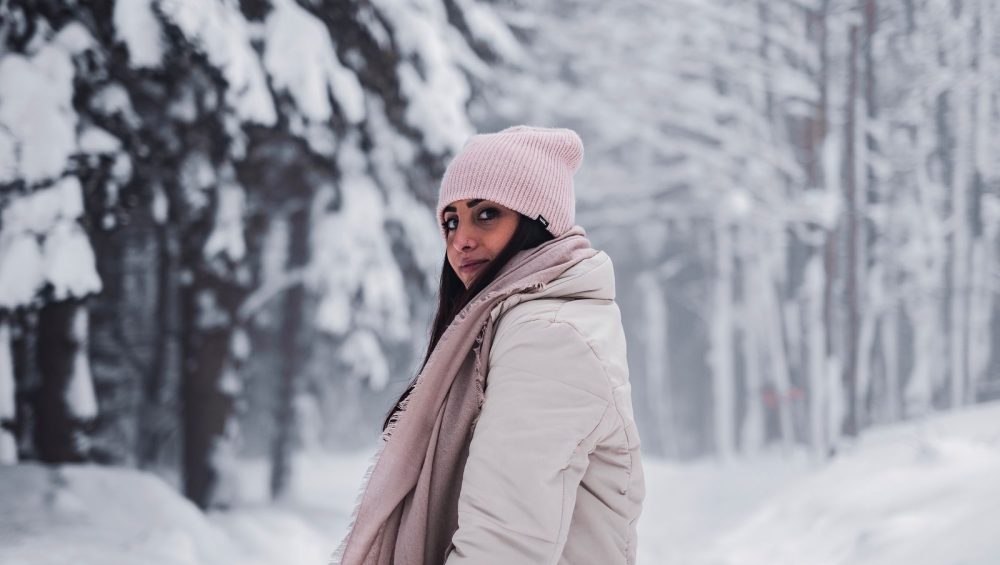 Woman in a winter coat and hat in a snowy forest