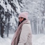 Woman in a winter coat and hat in a snowy forest