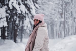Woman in a winter coat and hat in a snowy forest