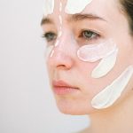 Close view of a woman's face with strokes of different textures on her cheek, nose and forehead, from a translucent gel to a thick white cream