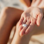 A single small dab of white cream resting on the fingers of an open hand in warm sunlight