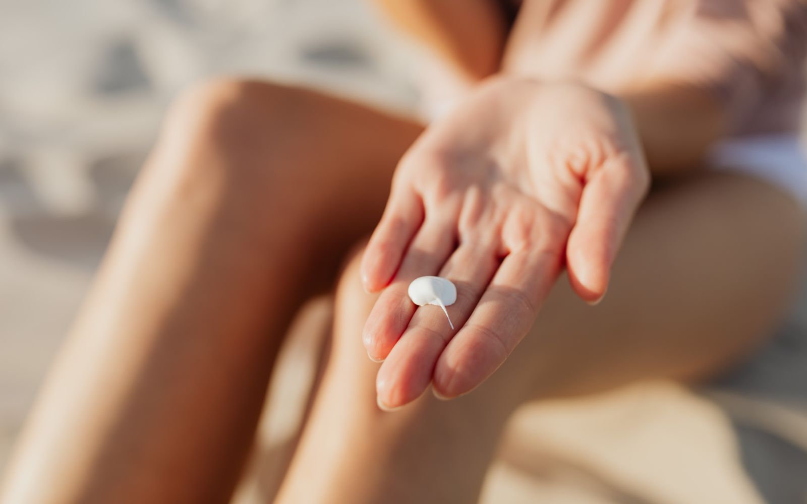 A single small dab of white cream resting on the fingers of an open hand in warm sunlight