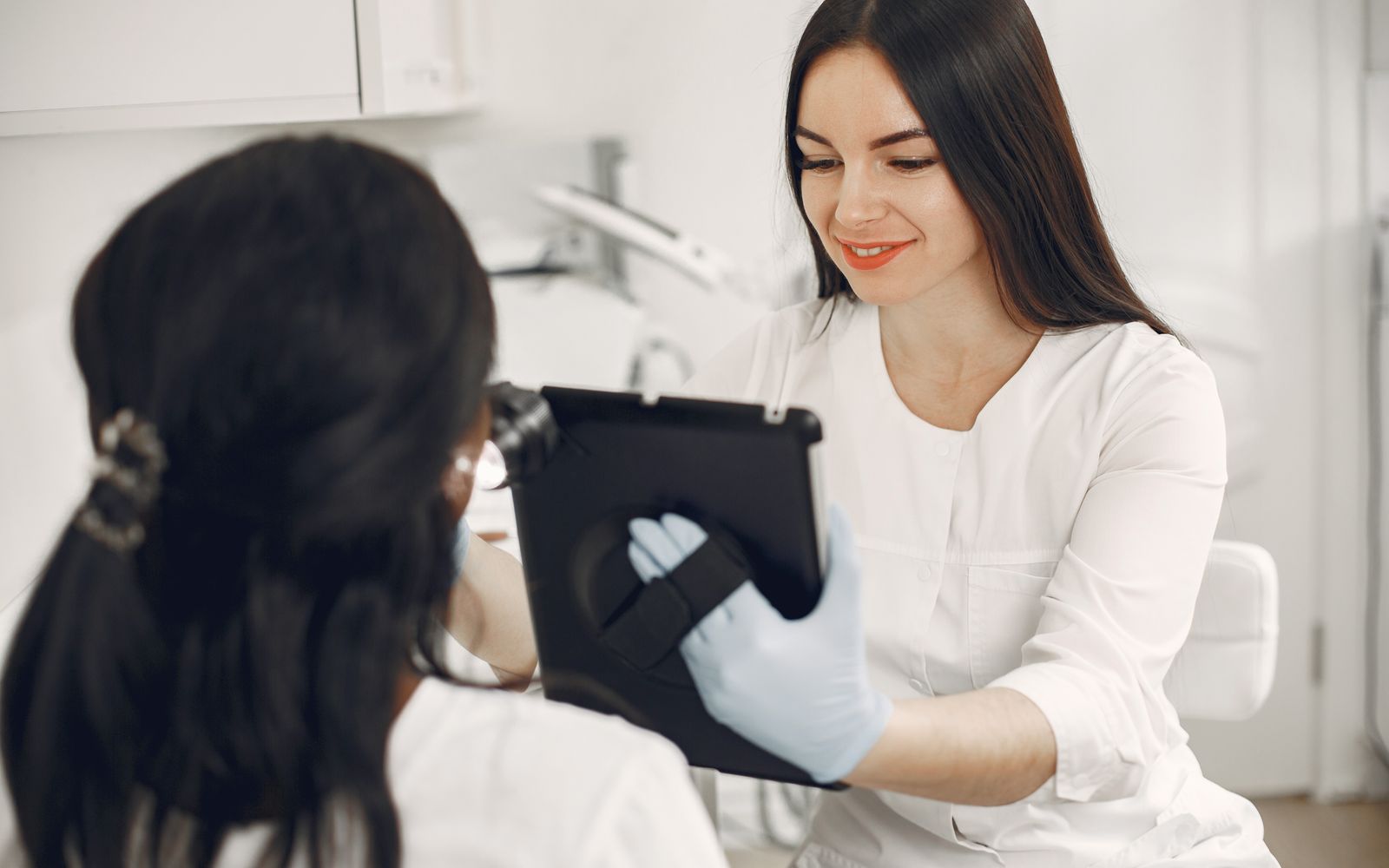 An aesthetician showing a client something on a tablet during a consultation in a bright treatment room