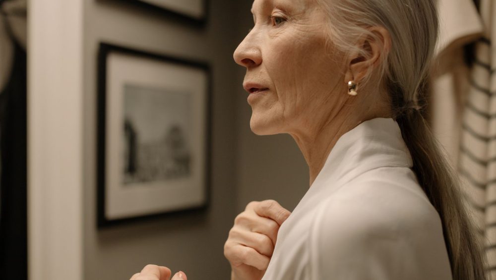 Profile of a woman in her sixties, jaw and neck in soft indoor light, unretouched