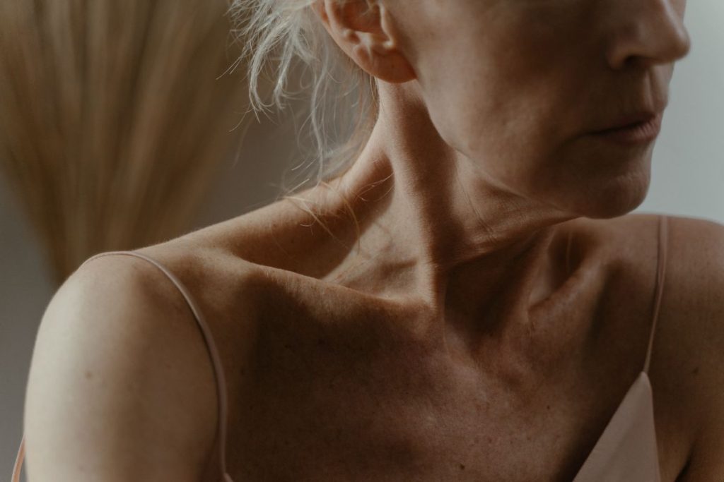 A mature woman's neck, collarbone and shoulder in soft light, no product in frame
