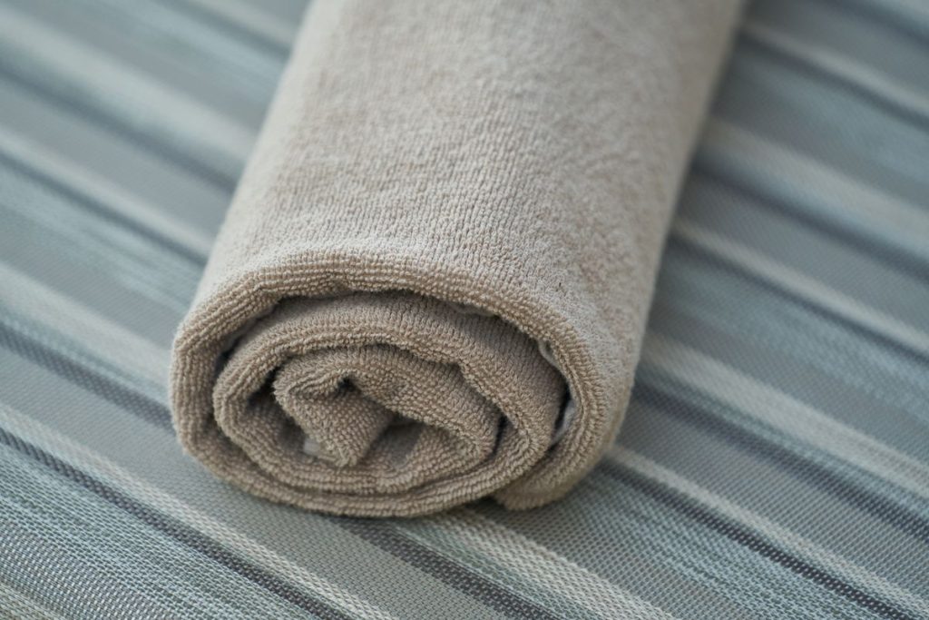 A soft, clean cotton cloth rolled on a striped surface