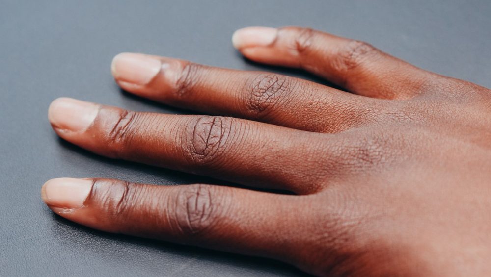 A relaxed hand resting on a soft gray surface in even light
