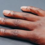 A relaxed hand resting on a soft gray surface in even light