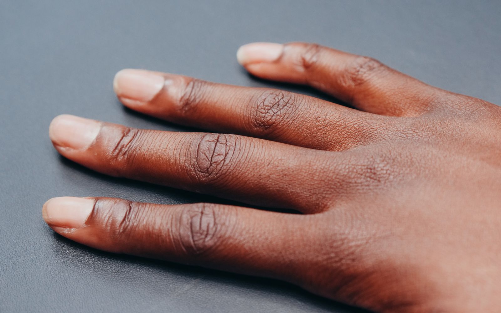 A relaxed hand resting on a soft gray surface in even light