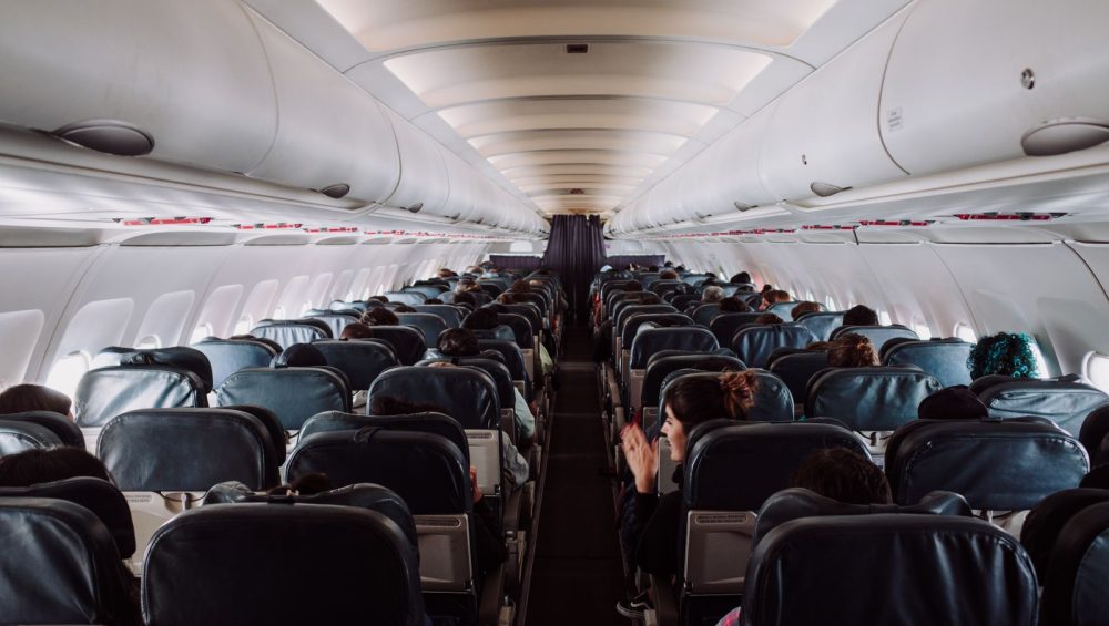 A view down the aisle of an aircraft cabin with passengers seated under soft overhead lighting