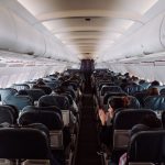 A view down the aisle of an aircraft cabin with passengers seated under soft overhead lighting
