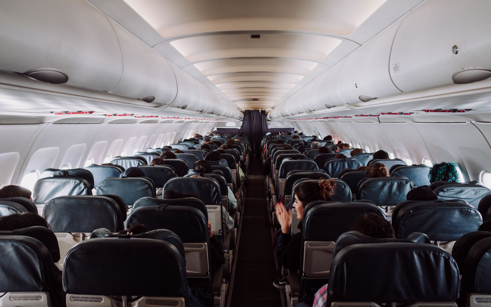 A view down the aisle of an aircraft cabin with passengers seated under soft overhead lighting