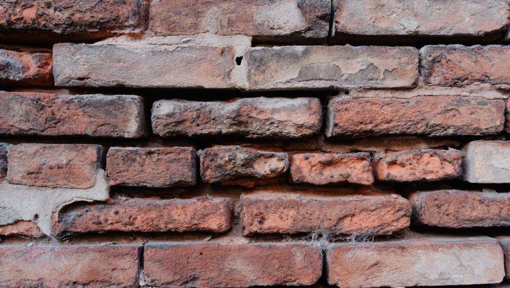 Close-up of an old red brick wall with pale mortar running between the bricks