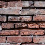 Close-up of an old red brick wall with pale mortar running between the bricks