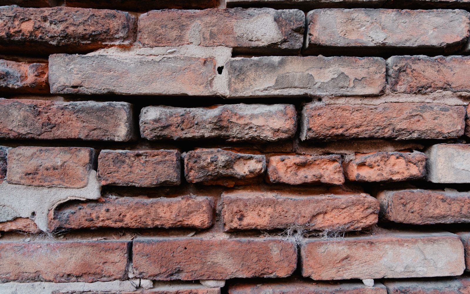 Close-up of an old red brick wall with pale mortar running between the bricks