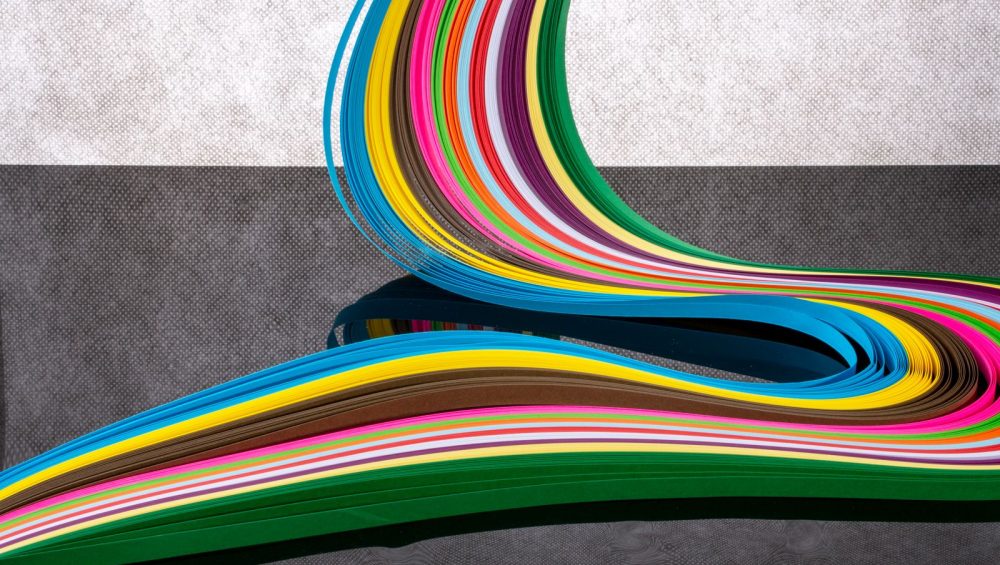 Curving bands of colored paper strips running from one color to the next, an abstract nod to the pH color scale